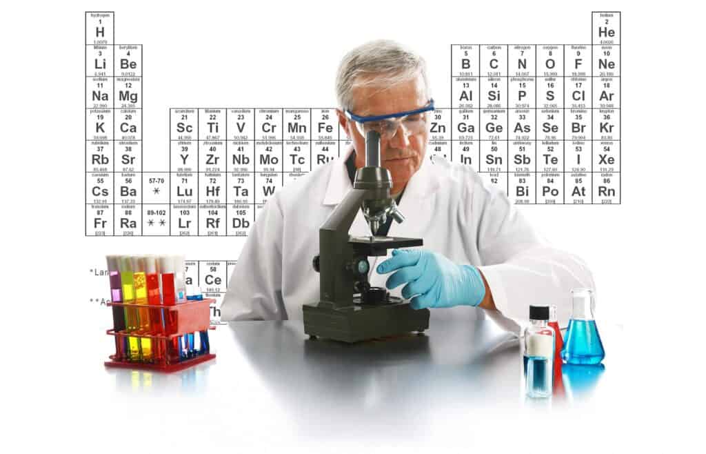 Chimico al microscopio con tavola periodica sullo sfondo, a simboleggiare l'analogia tra elementi chimici e le caratteristiche degli infissi in PVC.