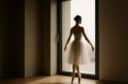 Ballerina in punta di piedi davanti a una grande finestra moderna, simbolo di leggerezza e armonia architettonica