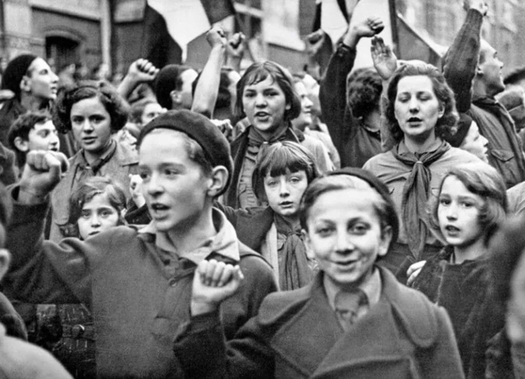 Fotografia di Robert Capa con folla e bambini durante manifestazione storica osservata come un’inquadratura narrativa